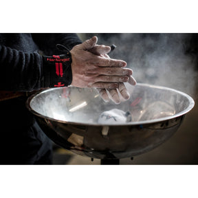 Chalk dust released from hands above a gym chalk bowl